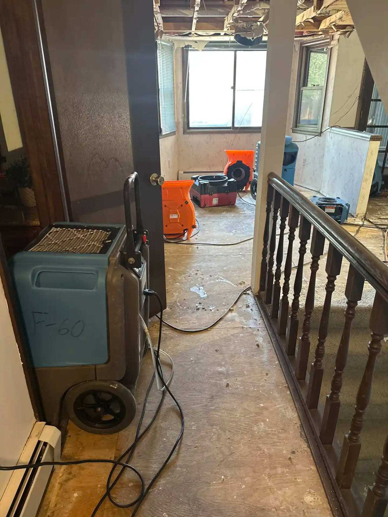 Dehumidifier on an upstairs landing below a ceiling opened after a leak