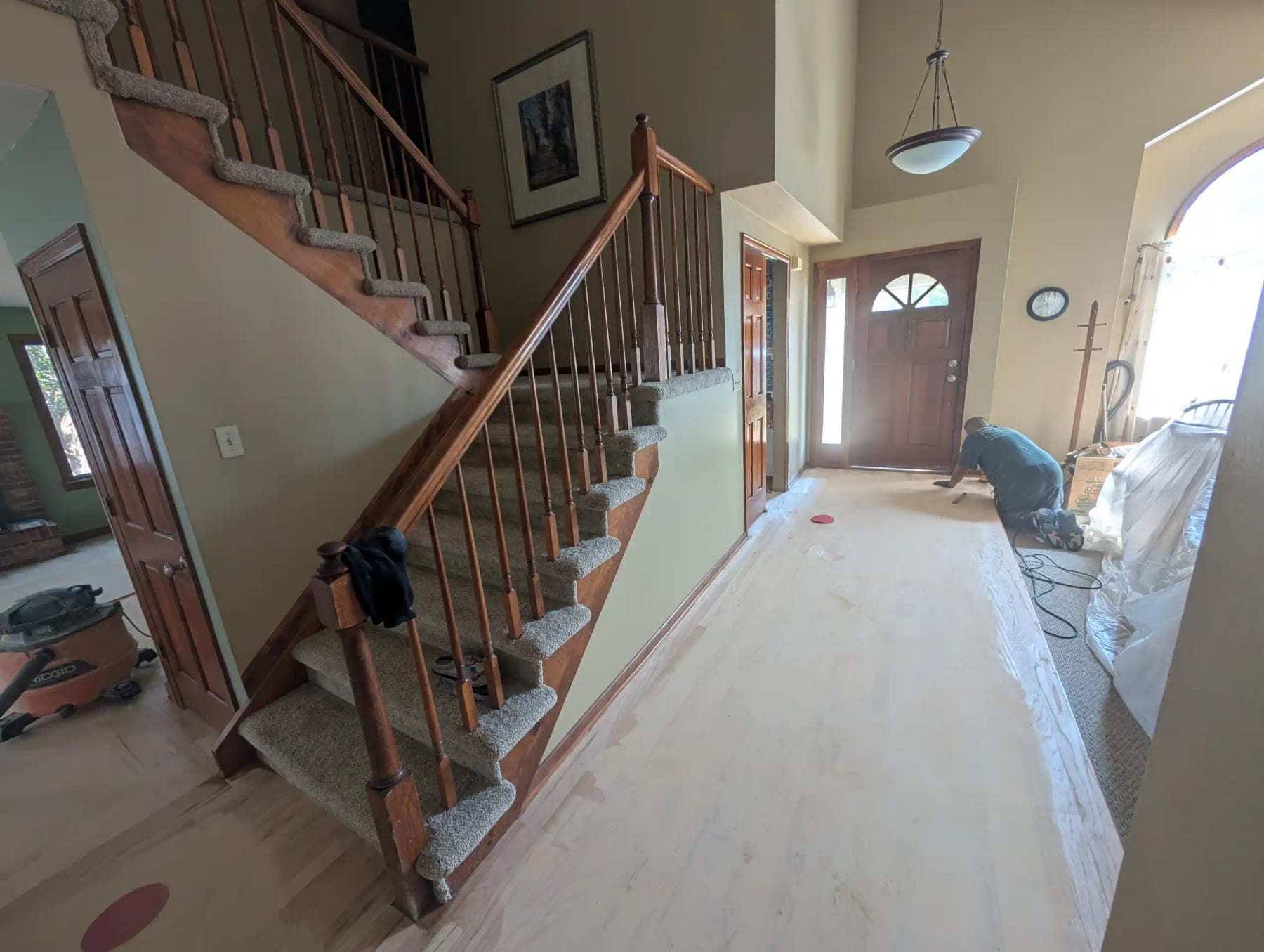 Entry hall with the flooring removed down to the subfloor and the stair protected